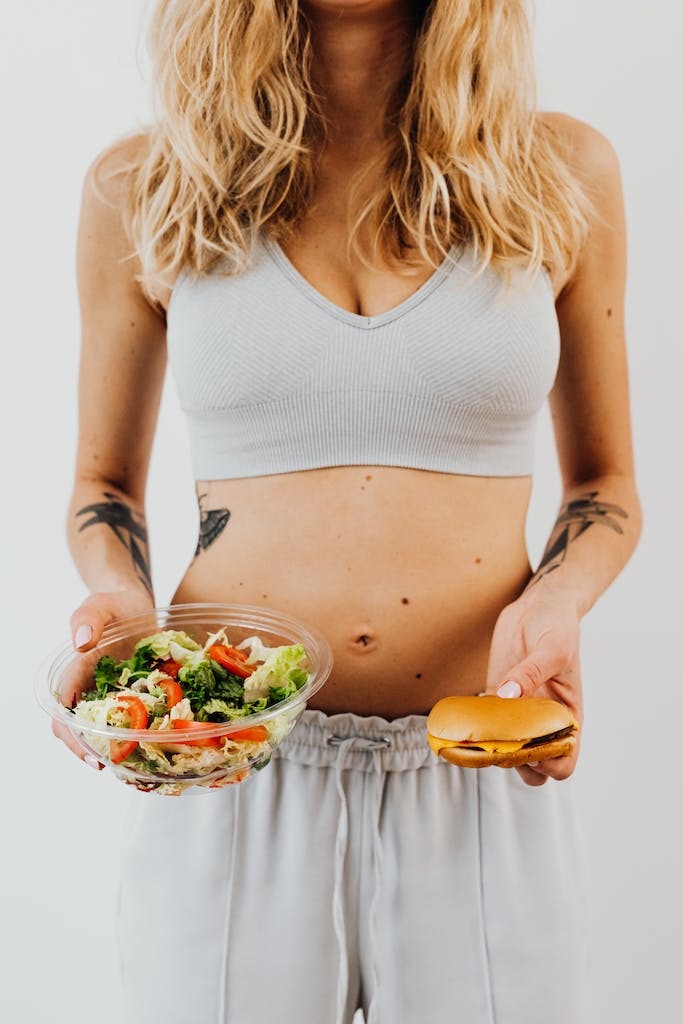 Woman Holding Burger and Bowl of Salad